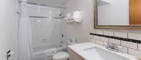 Un bagno con vasca, water, lavabo e specchio.