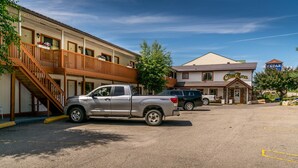 A motel with a two-story building, a covered parking area, and a visible staircase leading to the upper floor. - Cedar Motel (Radium Hot Springs)
