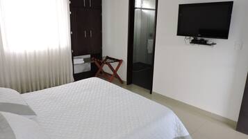 Een hotelkamer met een bed, een kledingkast, een televisie en een douchehoek.