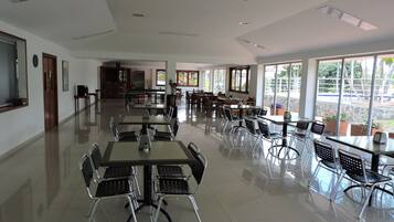 Un comedor amplio con varias mesas y sillas, ventanas grandes que ofrecen vistas al exterior, y un diseño interior moderno y limpio.