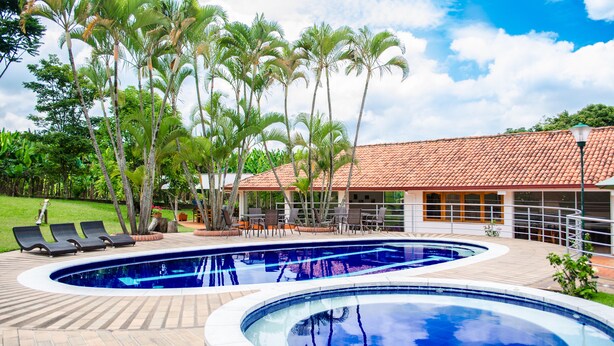 Una piscina con sillones de descanso y palmeras.
