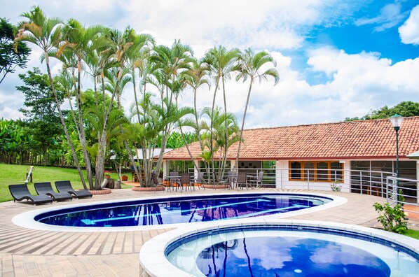 Una piscina al aire libre, sillones reclinables de piscina