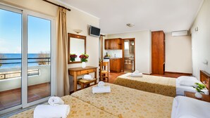 A hotel room with two beds, a balcony with a view of the sea, a kitchenette, and a TV. - Panos Beach Hotel (Platanias)