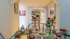 A dining area with a glass table, metal tea set, and a vase with a rose. - In Club Palmeraie Resort (Marrakech)