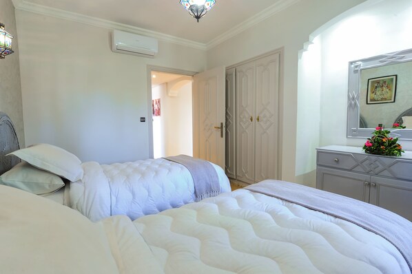 A bedroom with two beds, a wardrobe, and a mirror.