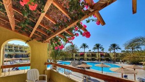 A balcony with a view of a pool area, including multiple pools and palm trees. - Eurotel Palm Beach Resort (Hurghada)