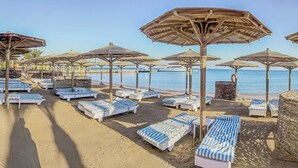 A beach with sun loungers and umbrellas, a clear sky, and a calm sea. - Eurotel Palm Beach Resort (Hurghada)