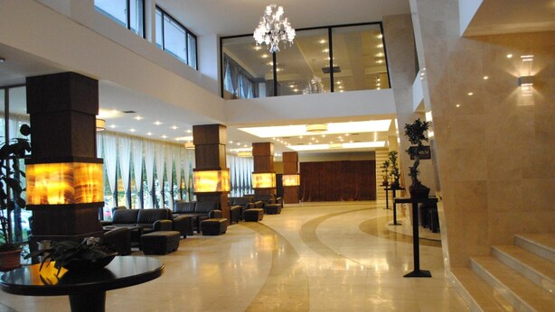 Un hall d’entrée spacieux avec un espace salon aux lignes courbes, de grandes fenêtres et un lustre.