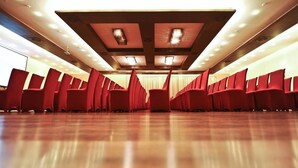 Une salle de conférence avec des rangées de chaises rouges et un plancher en bois.