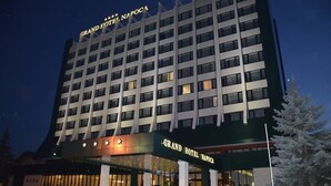 Un hôtel à plusieurs étages, reconnaissable à son grand panneau indiquant « GRAND HÔTEL NAPOCA ».