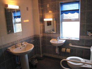 A bathroom with two sinks, a toilet, a window with a view, and a mirror. - Colston Hall Cottages (Woodbridge)