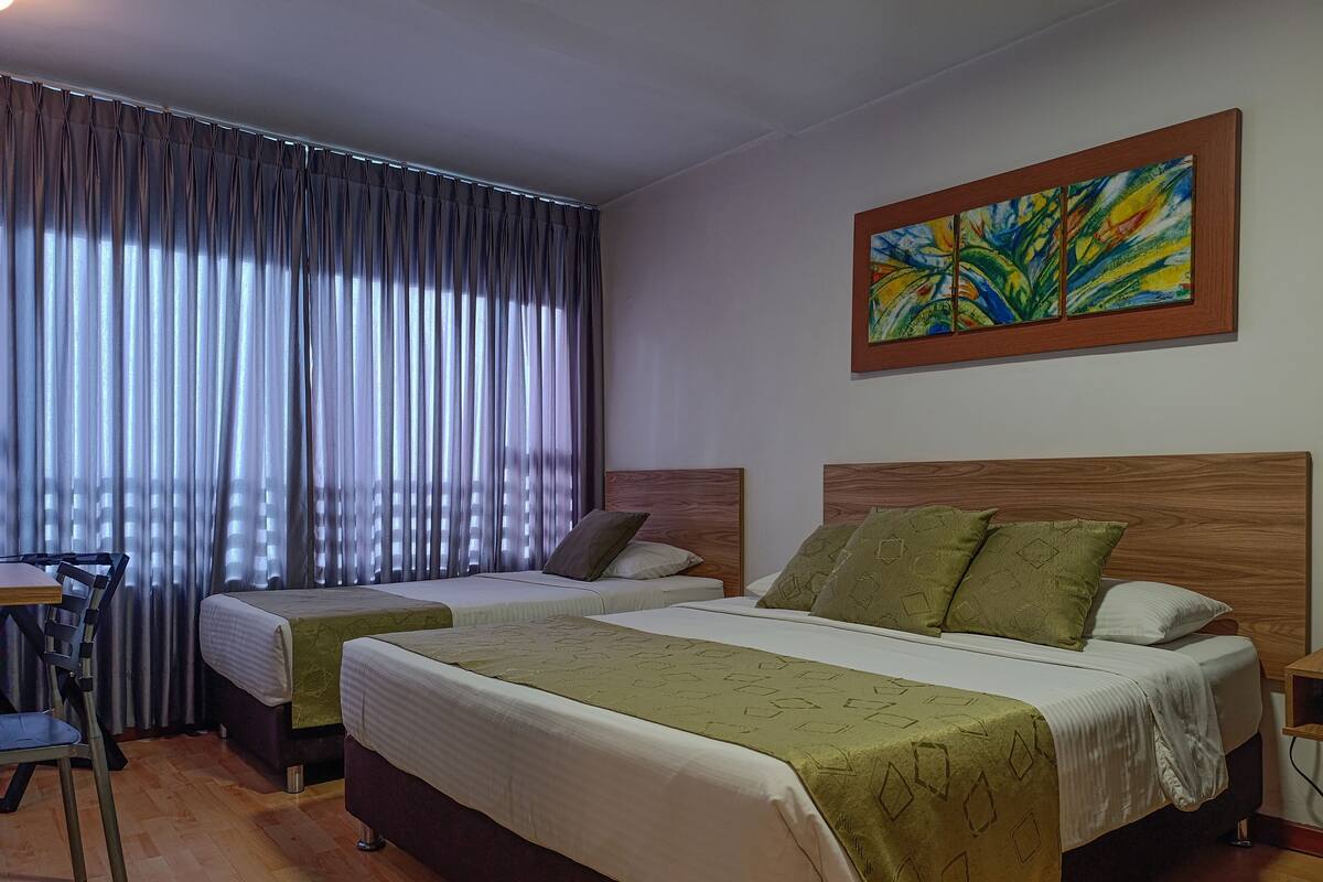 A hotel room with two beds, a desk, and a chair.