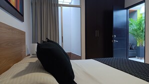A hotel room with a bed, a large window, a door leading to a balcony, and a dark wardrobe. - Hotel Volare (Armenia)