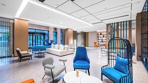A modern lobby with a seating area, a blue sofa, and a black chair with a blue cushion. - Hangzhou Wassim Resorts Hotel  (Hangzhou)