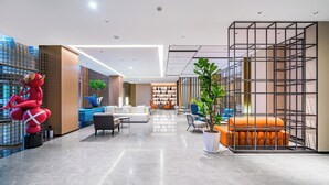 A modern lobby with a large red sculpture, a seating area with orange and blue furniture, and a plant in the center. - Hangzhou Wassim Resorts Hotel  (Hangzhou)