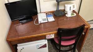 Ein Schreibtisch aus Holz mit einem Computermonitor, einem Telefon und einer Kaffeemaschine.