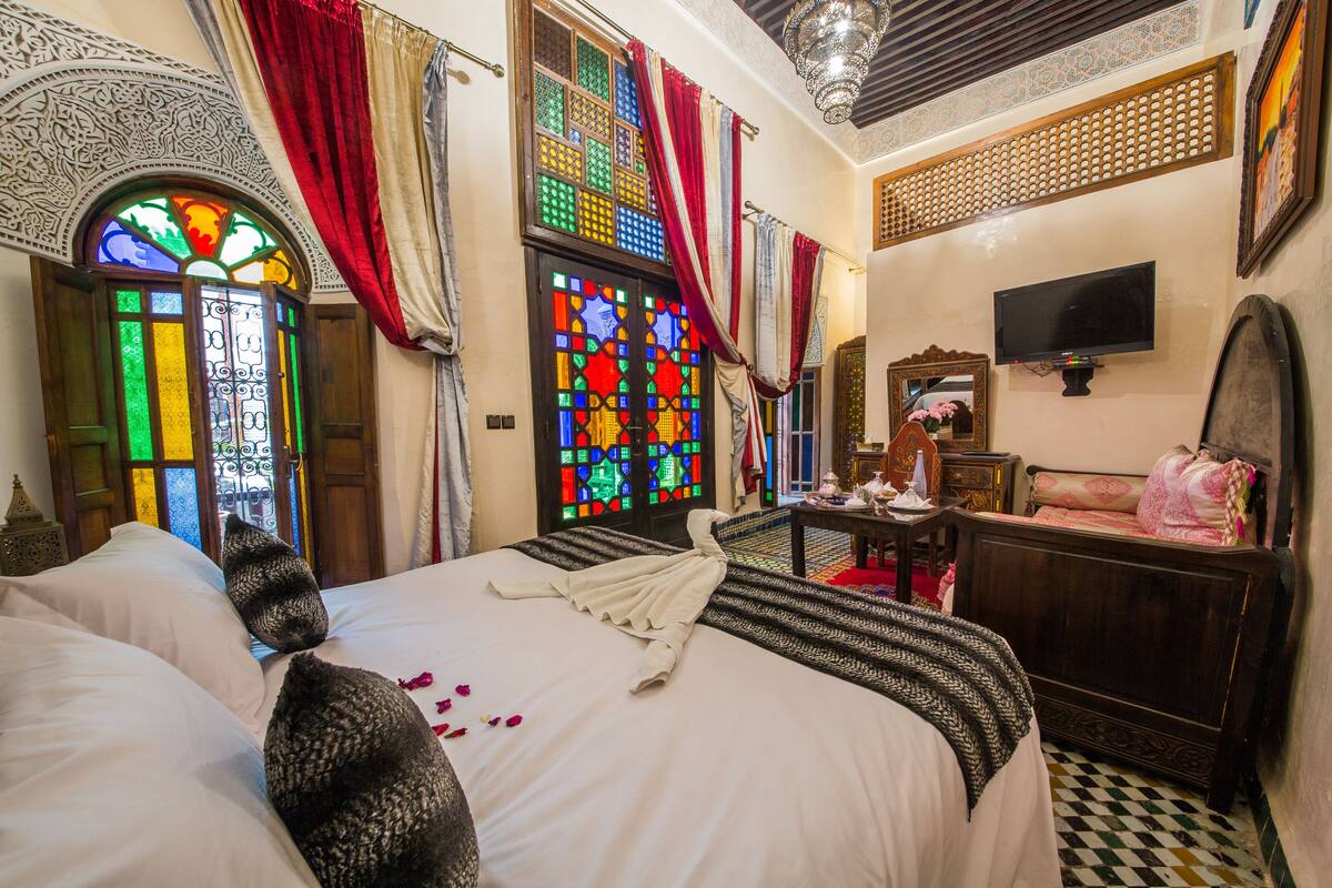 A traditional room with a bed, a television, and a mirror.