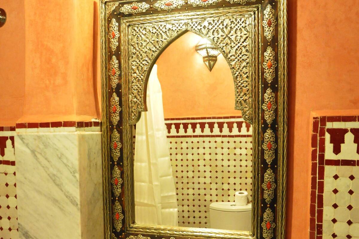 A bathroom with a marble sink, ornate mirror, and patterned tiles.