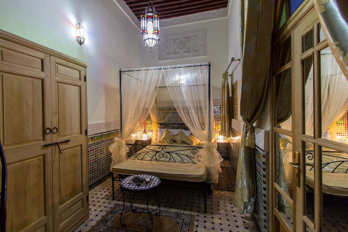 A room with a four-poster bed, a small round table, and a decorative lantern.