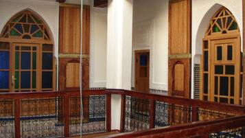 Quarto com portas de madeira, parede branca e corrimão de madeira.