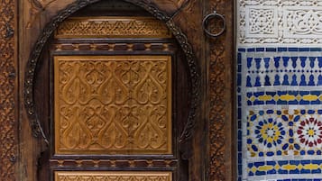 Uma porta de madeira com entalhes detalhados e uma maçaneta de metal em forma de anel.