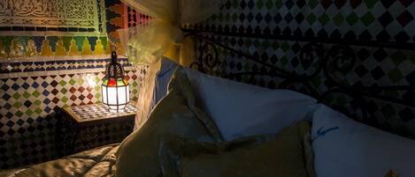 A bed with patterned pillows and a nightstand with a decorative lantern.