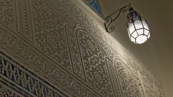Un muro decorato con dettagliati motivi geometrici e floreali, un lampadario appeso e un soffitto con decorazioni blu e bianche.
