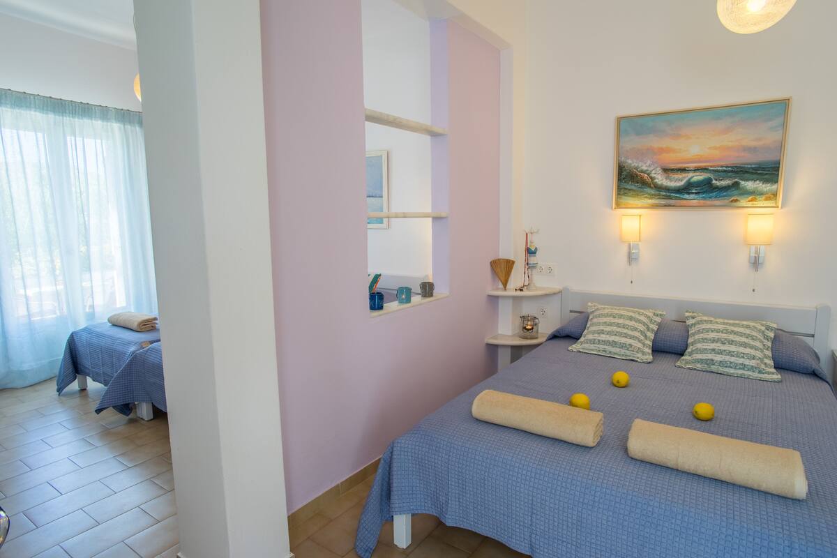 Un dormitorio con una cama, almohadas y un cuadro de un paisaje marino.