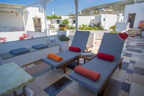 Terraço no telhado com cadeiras de descanso, uma mesa pequena e vista dos edifícios ao redor.