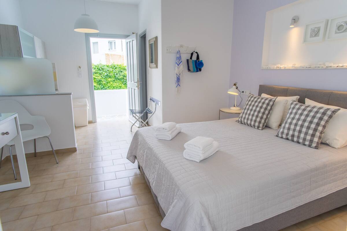 Un dormitorio ordenado con cama, mesita de noche y escritorio con silla.
