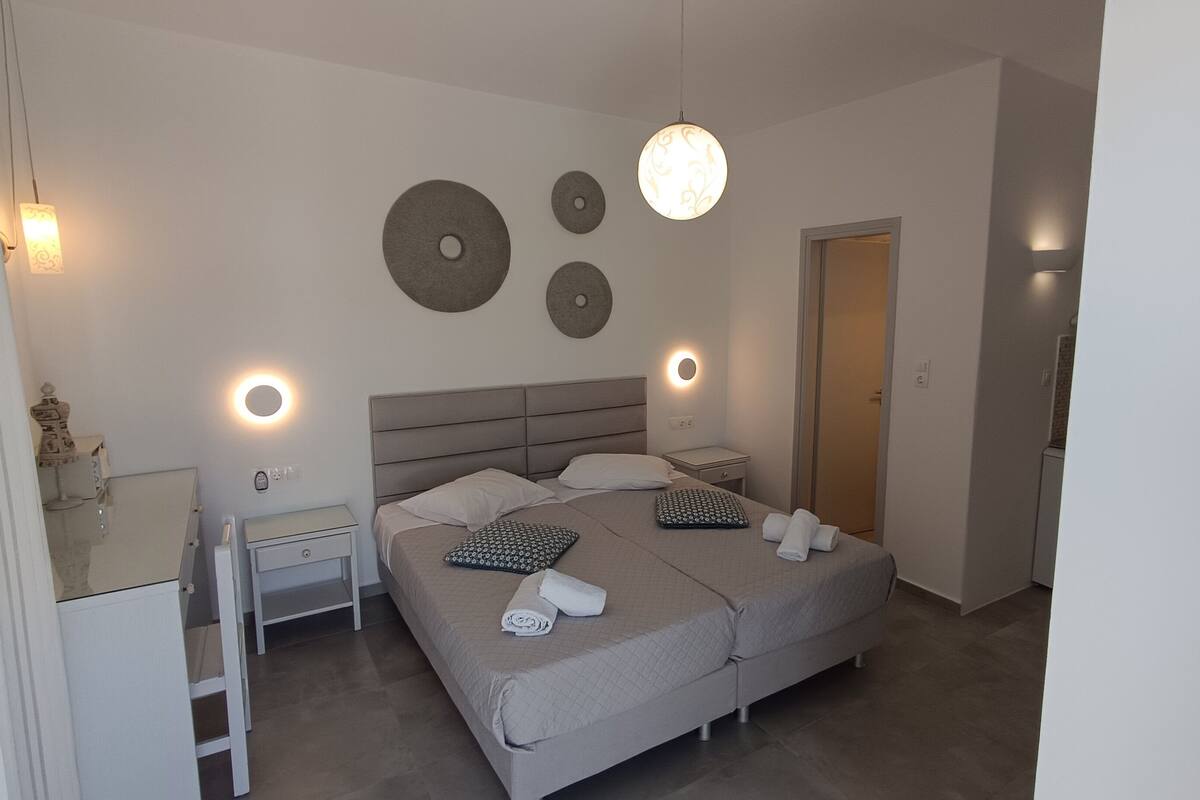 Un dormitorio moderno con una cama doble, mesitas de noche, un espejo y adornos en la pared.