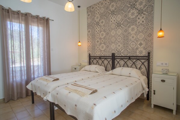 Un lit double avec une tête de lit à motifs, deux tables de chevet, une lampe de chevet et un mur orné d’un motif décoratif.