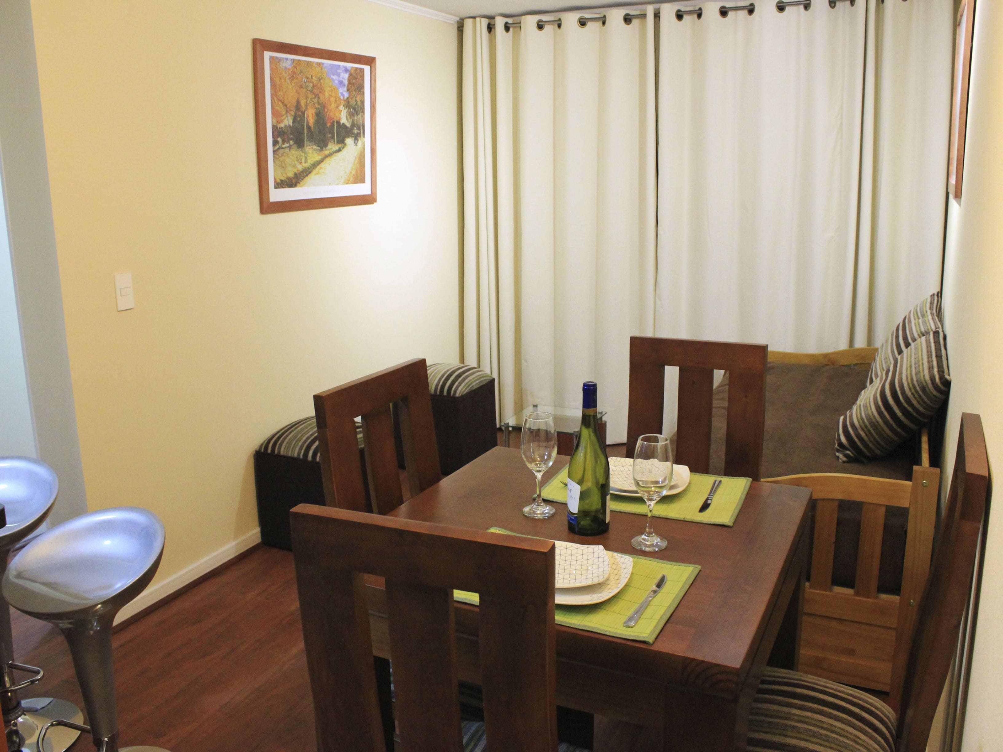 A dining area with a wooden table, chairs, and a painting on the wall.