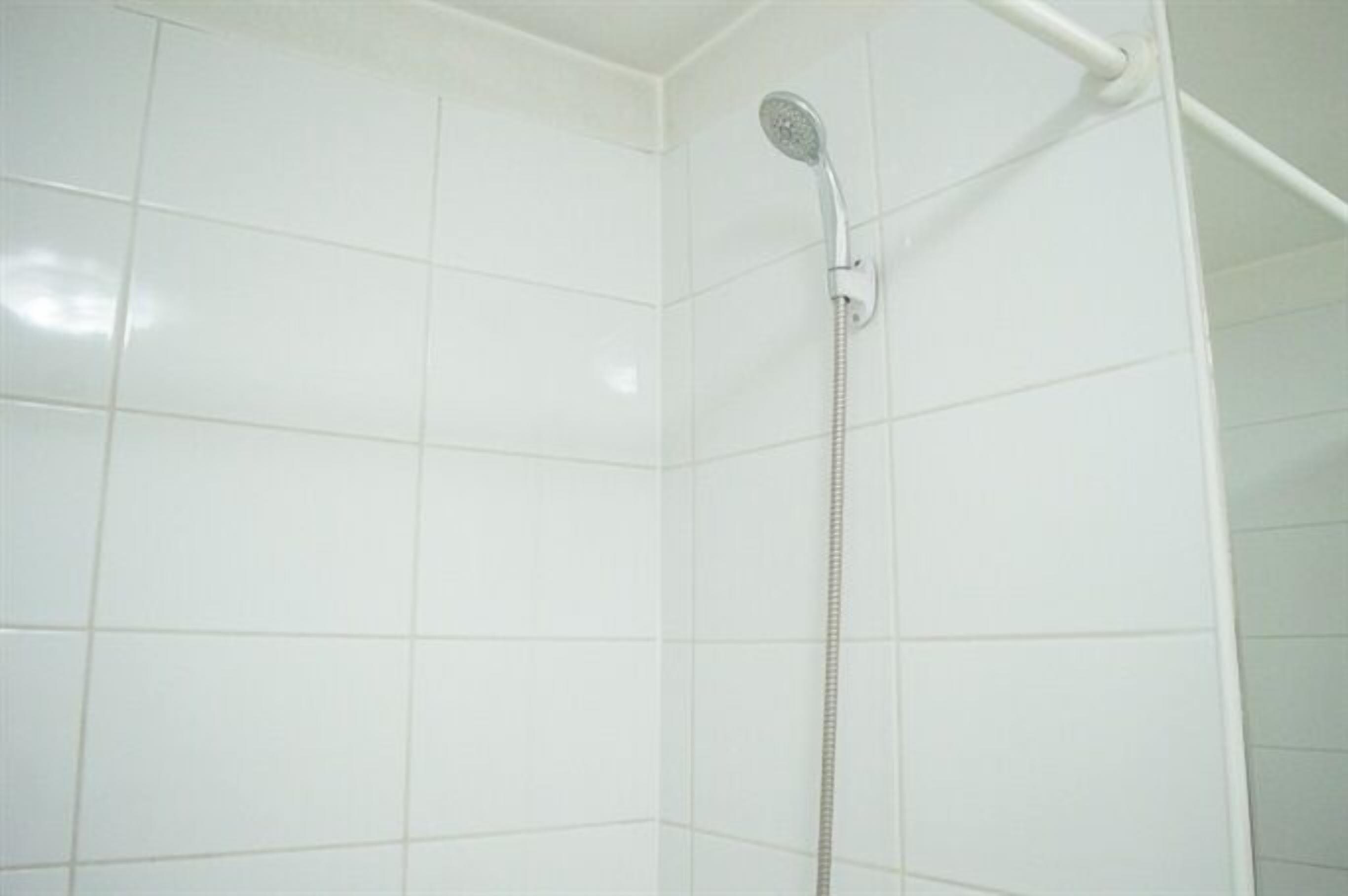 A shower with a handheld showerhead in a tiled bathroom.
