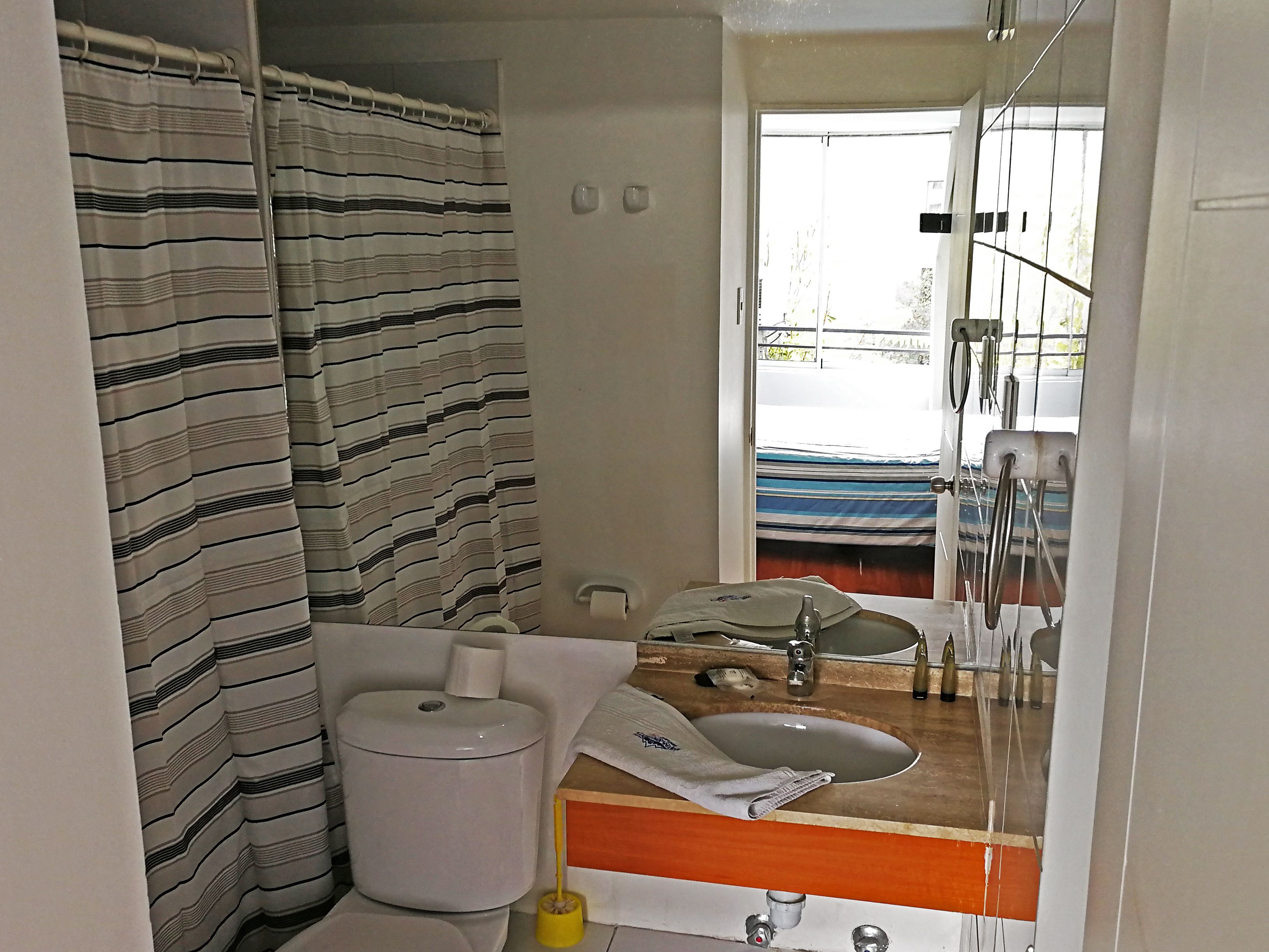 A bathroom with a striped shower curtain, a toilet, a sink, and a mirror.