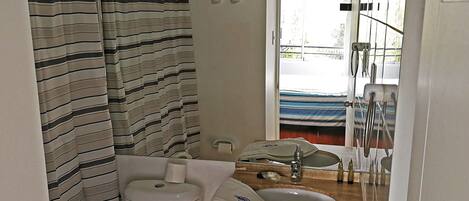 A bathroom with a striped shower curtain, a toilet, a sink, and a mirror.