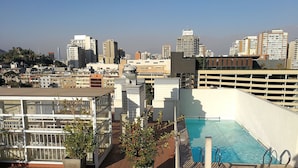 A rooftop pool area with a view of the city skyline, including high-rise buildings and a clear sky. - Amistar Plaza París (Santiago)