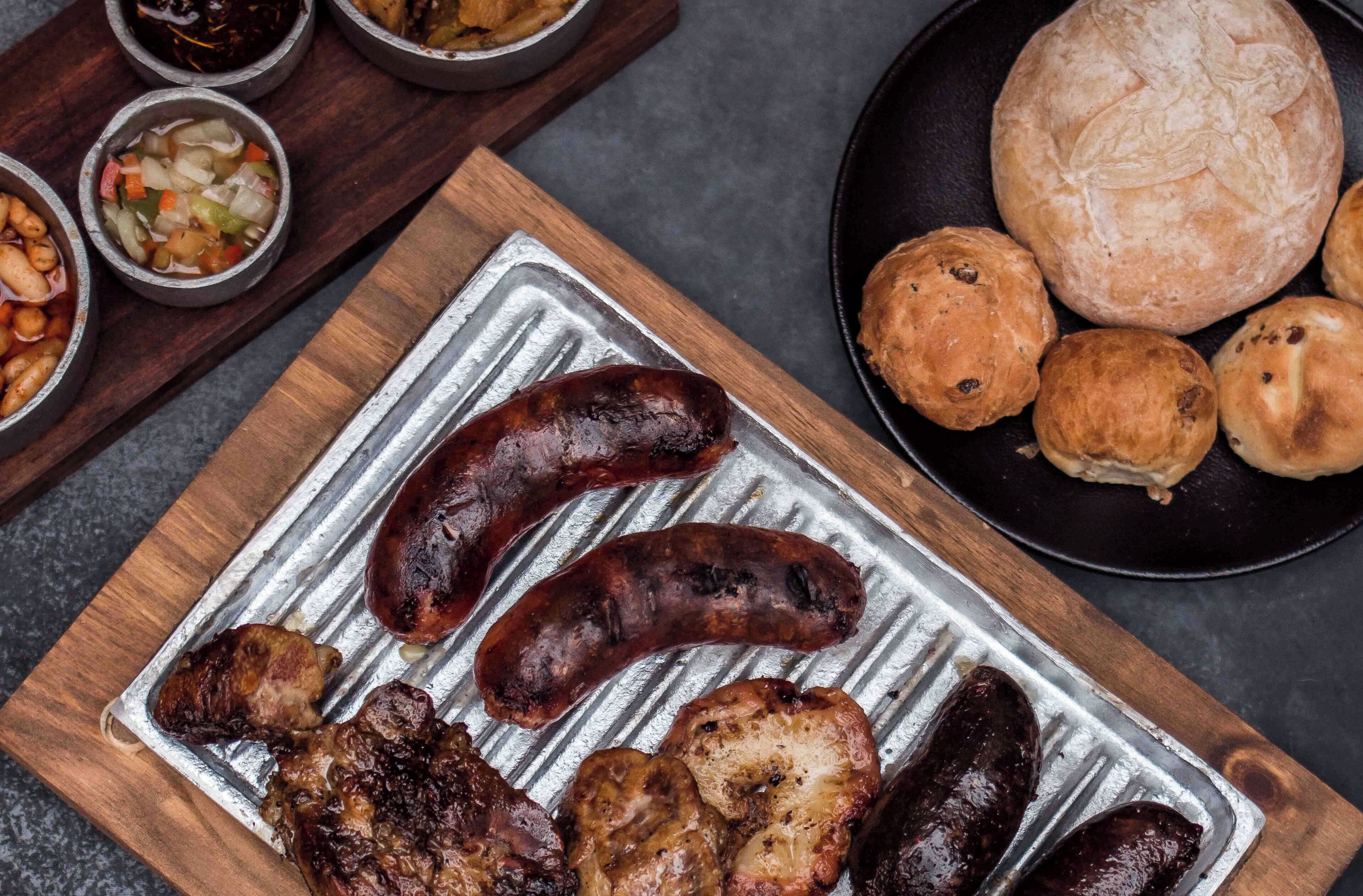 A tray of grilled sausages and meats on a metal surface.