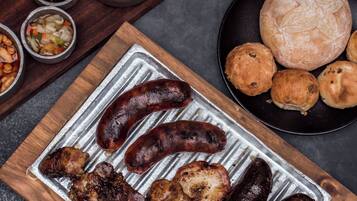 A tray of grilled sausages and meats on a metal surface.