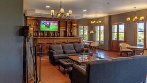 A spacious living room with a bar area, comfortable seating, and a large TV screen. - Wyndham Garden Luján (Luján)