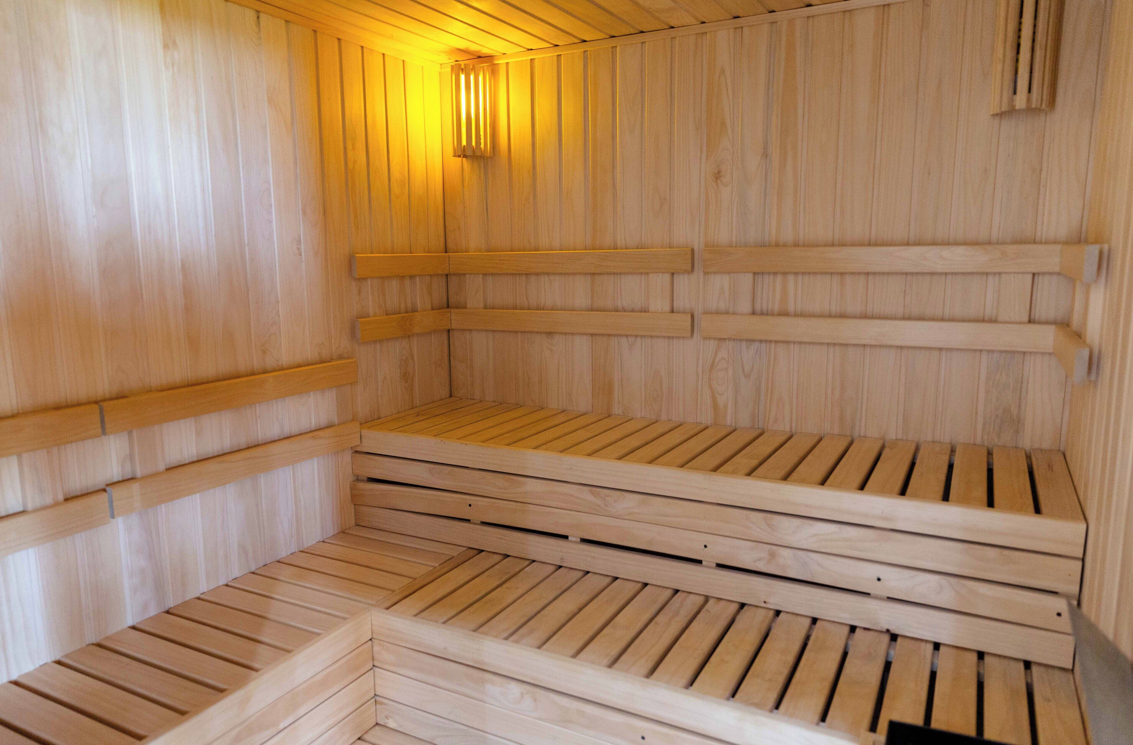 Sauna, jossa on puiset penkit ja kalteva lattia.