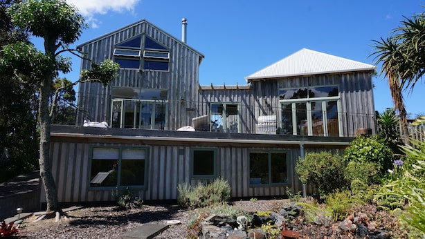 Una casa moderna de dos pisos con ventanas amplias y un balcón.