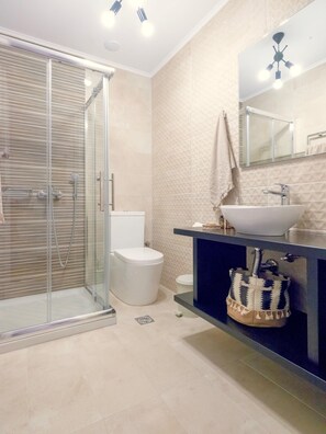 Une salle de bain moderne avec une douche à parois de verre, des toilettes blanches et un meuble-lavabo avec un évier et un miroir.