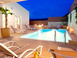 A pool area with lounge chairs and a potted plant.