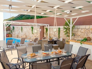 An outdoor dining area with a pool and stone walls. - Sky (Rethymno)
