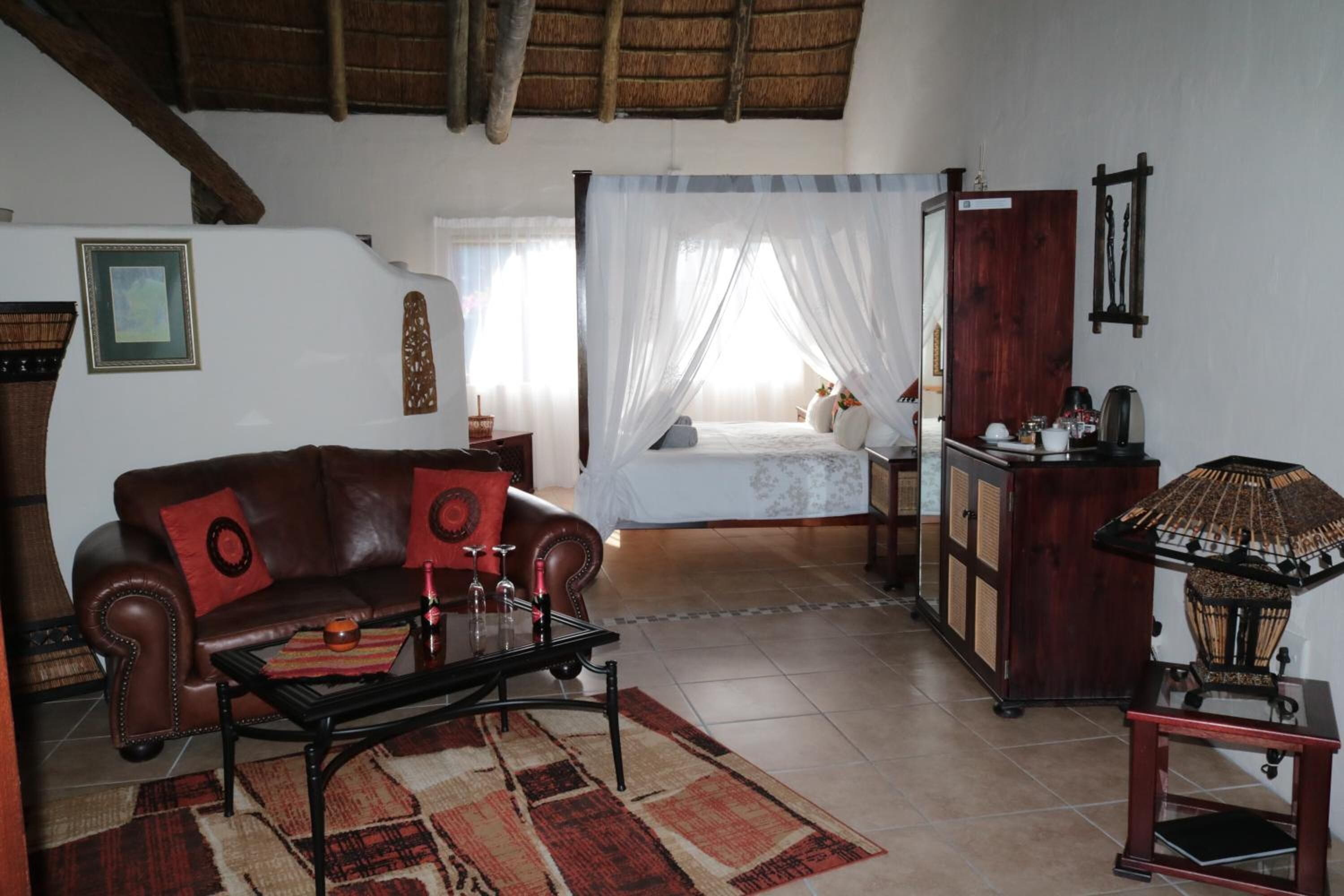 Una sala de estar con sofá, mesa de centro, cama con dosel, aparador y lámpara.