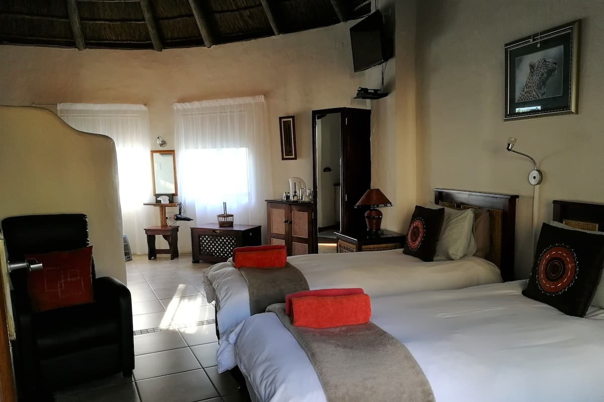 A hotel room with two beds, a desk, a chair, a TV, and a mirror.