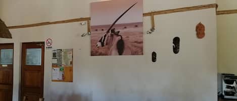 A room with a wooden ceiling, a wall-mounted lamp, a framed picture of an animal, a no-smoking sign, and a bulletin board with various notices.