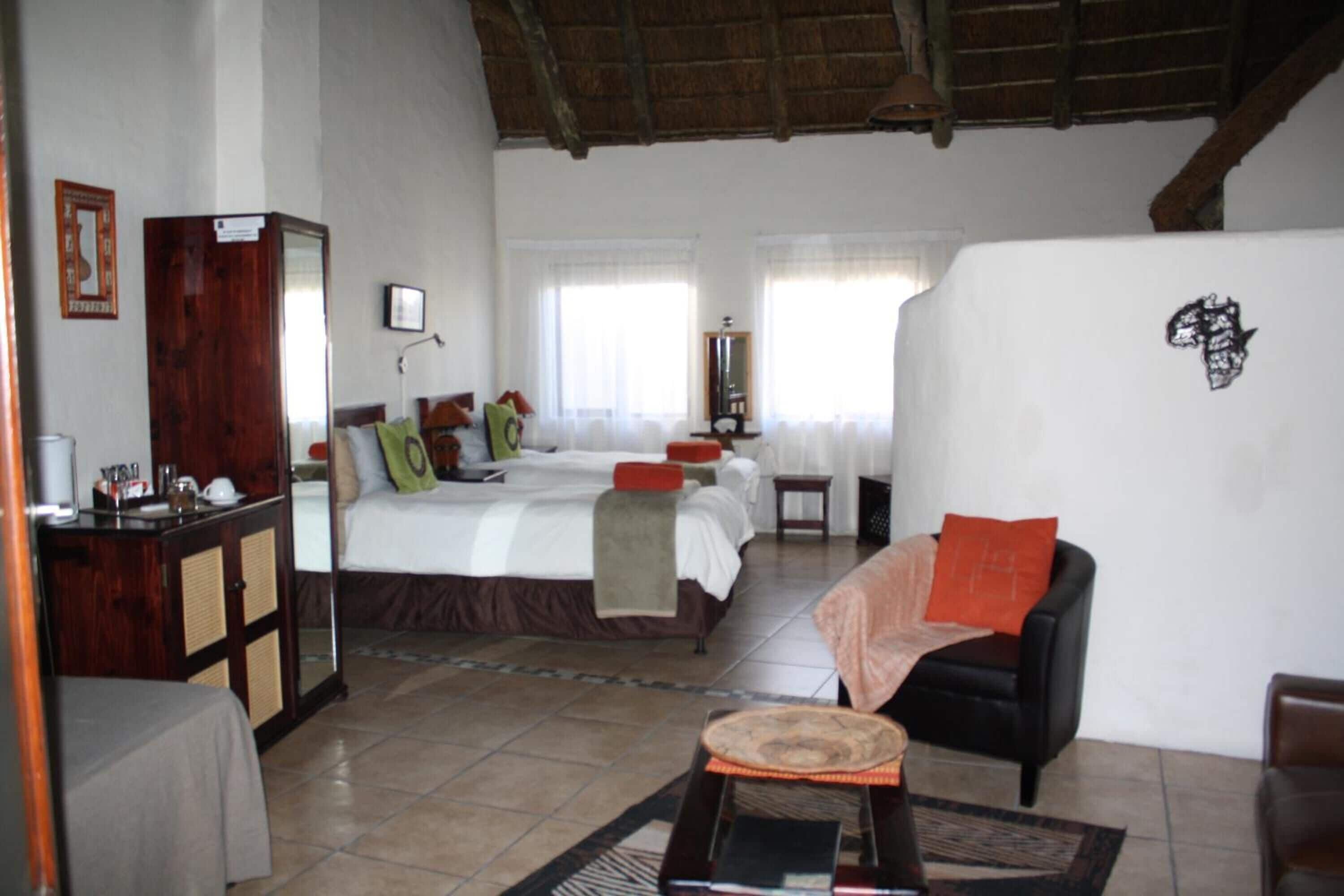 A hotel room with a bed, a desk, a chair, and a small table.