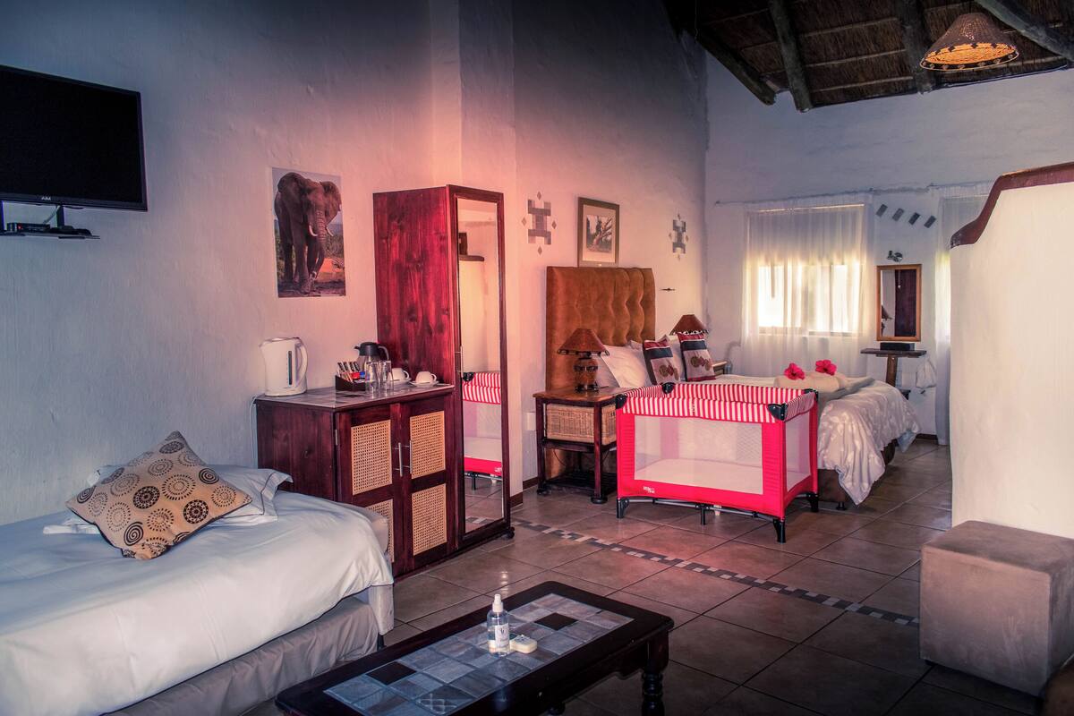 A hotel room with a bed, a sofa, a coffee table, a TV, a wooden cabinet, and a mirror.